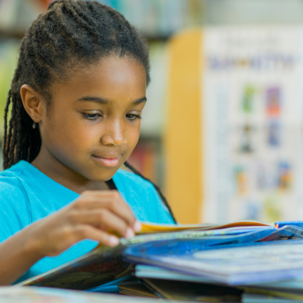 An elementary school girl learning to read at her desk. 